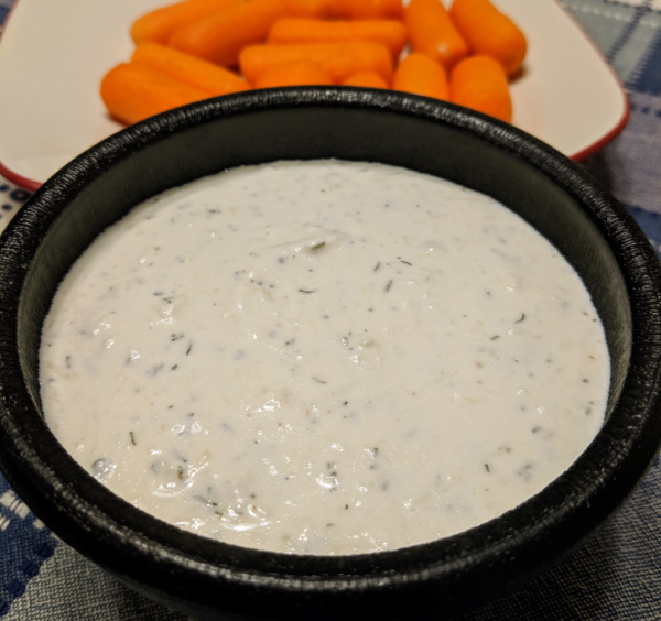 Tzatziki sauce in bowl with carrots in background